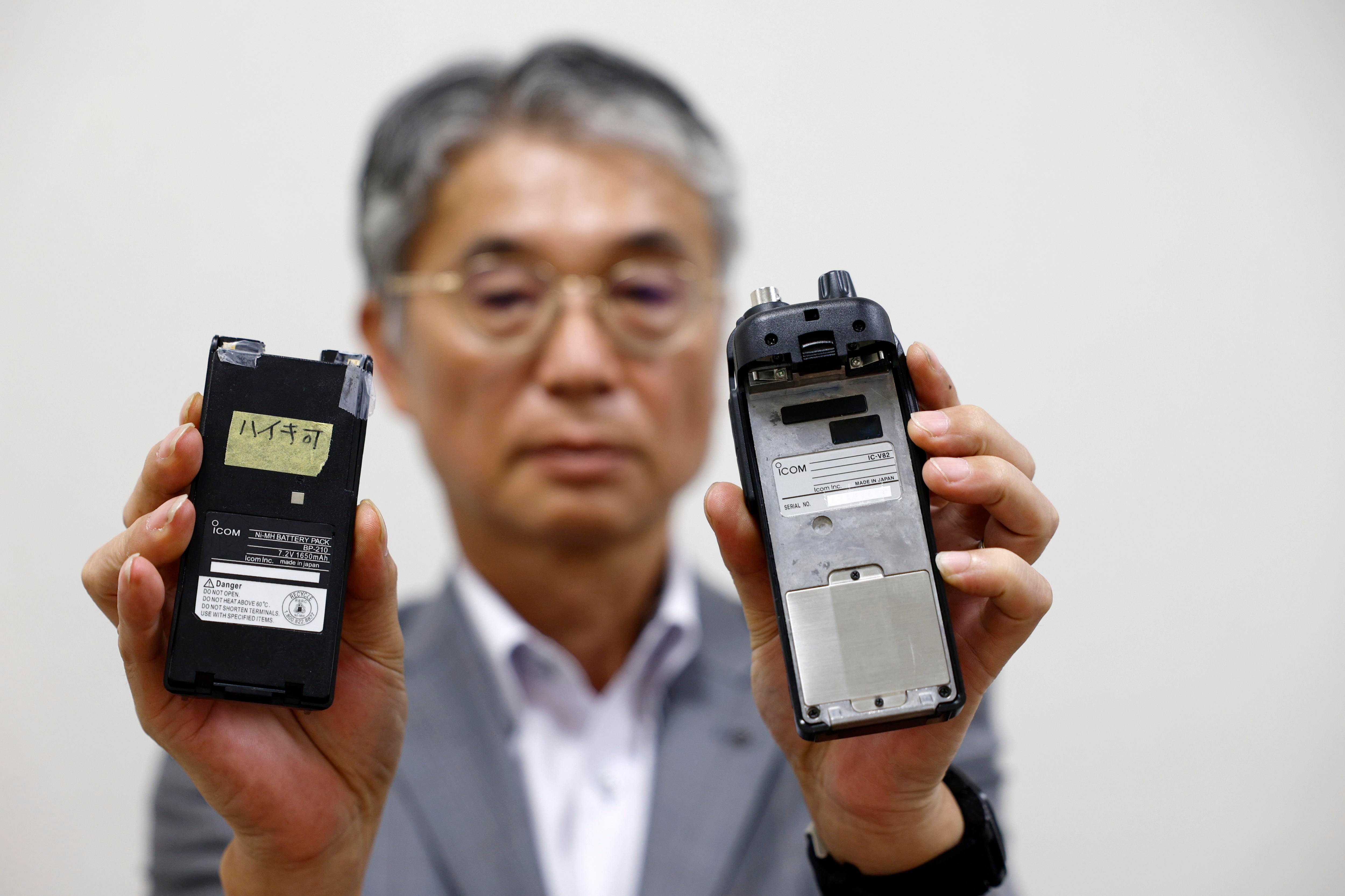 El director del fabricante japonés de walkie-talkie Icom Inc., Yoshiki Enomoto, muestra su aparato de radio modelo IC-V82 y su batería (L) en la sede central de la empresa en Osaka, (EFE/EPA/FRANCK ROBICHON)
