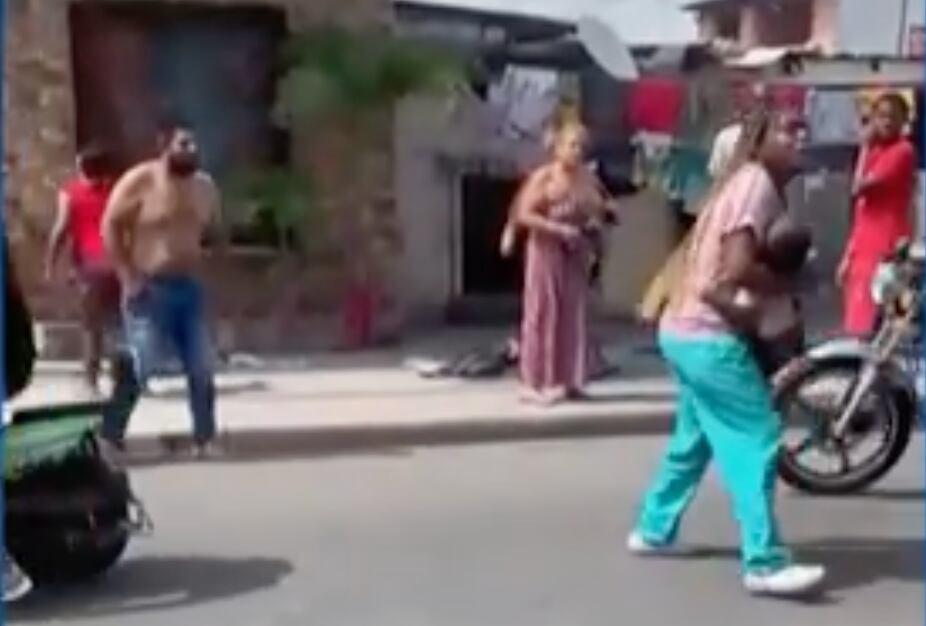 Una mujer carga en brazos a uno de los menores impactados por las balas de los sicarios. (Captura de pantalla)