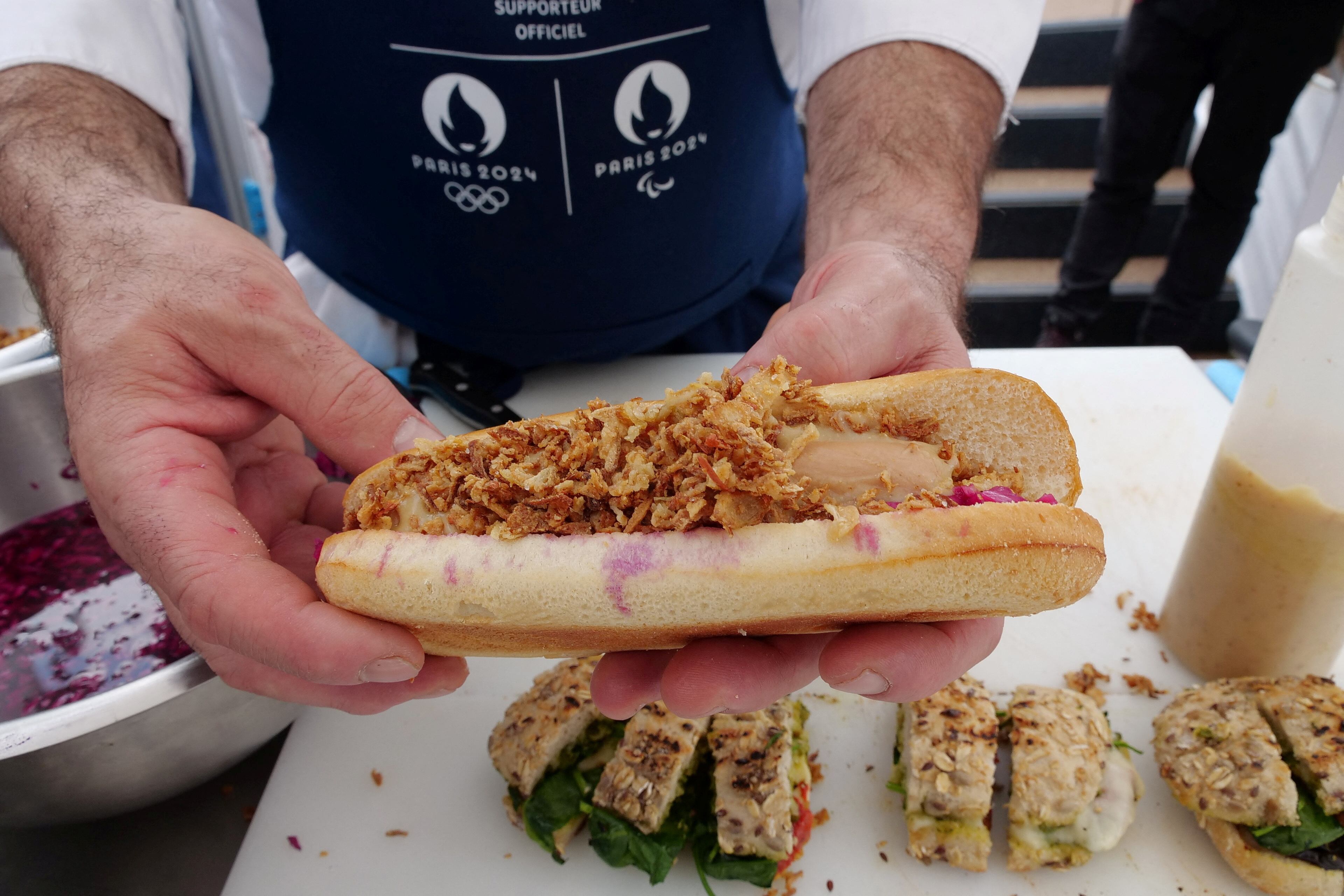 Stephane Chicheri, chef ejecutivo de Sodexo Live, sostiene un hot dog vegetariano que está disponible para consumir en la Villa Olímpica de Paris 2024 (REUTERS/Lucien Libert/Archivo)