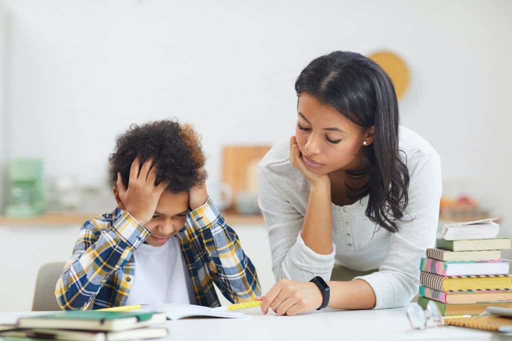 Una mujer ayuda a hacer las tareas escolares a un niño con TDAH (Ready Kids Occupational Therapy)