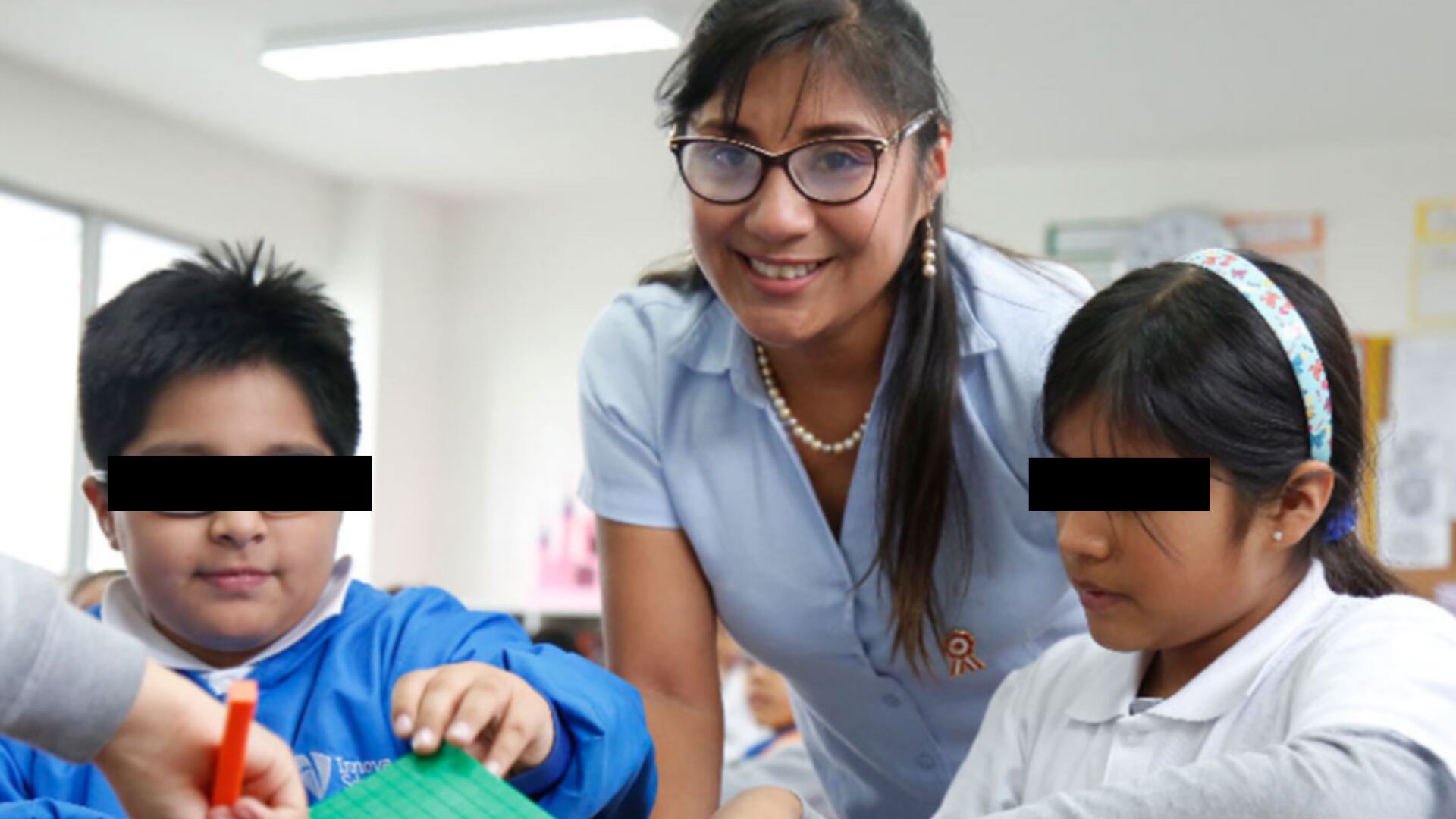 Una maestra juega con dos alumnos, en Perú.