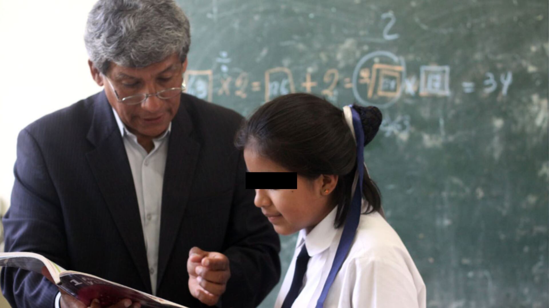 Un profesor enseña a una alumna un texto, en un colegio de Perú.