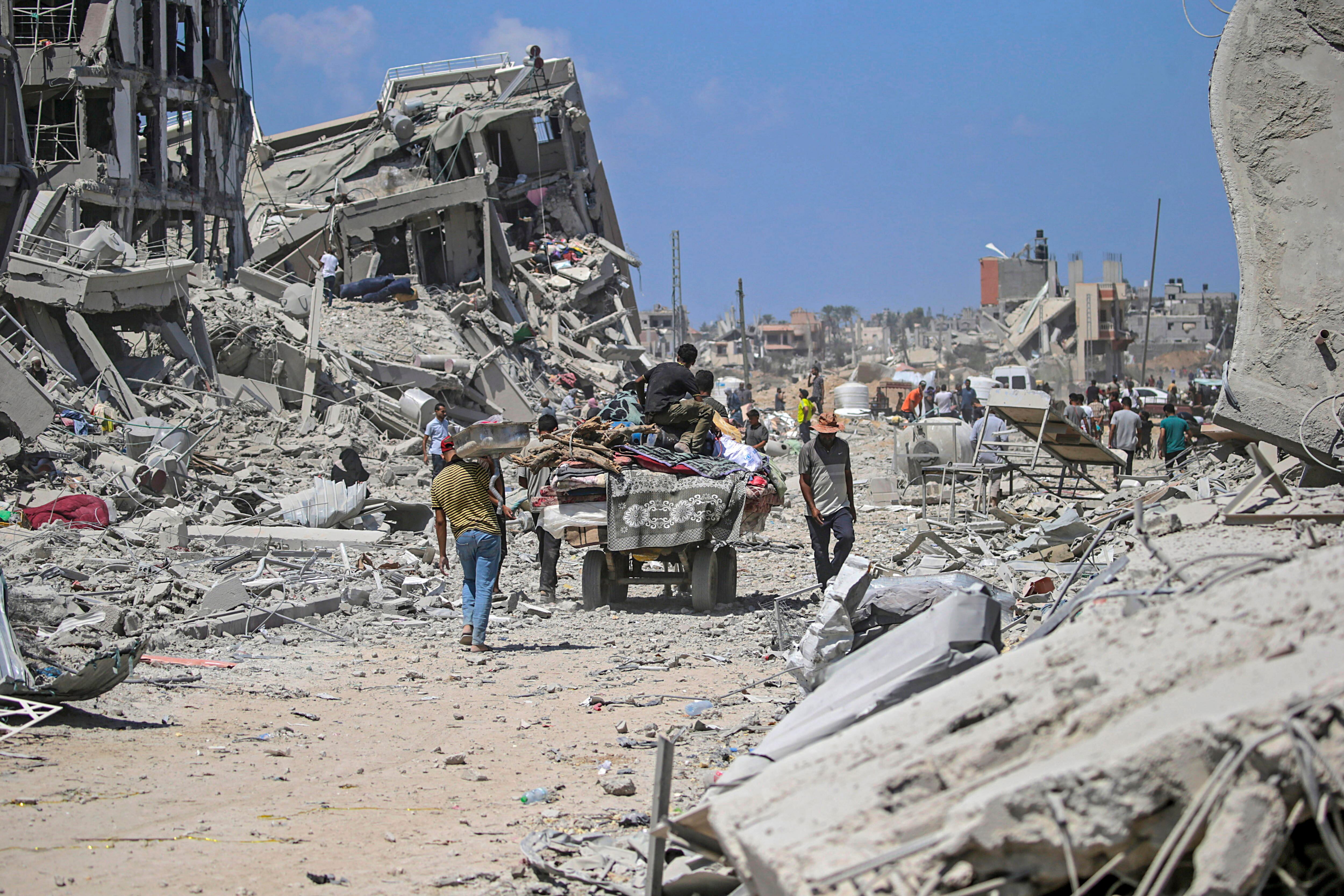 Palestinos caminan entre casas destruidas en la ciudad de Deir Al Balah, en la Franja de Gaza (EFE/EPA/MOHAMMED SABER/Archivo)