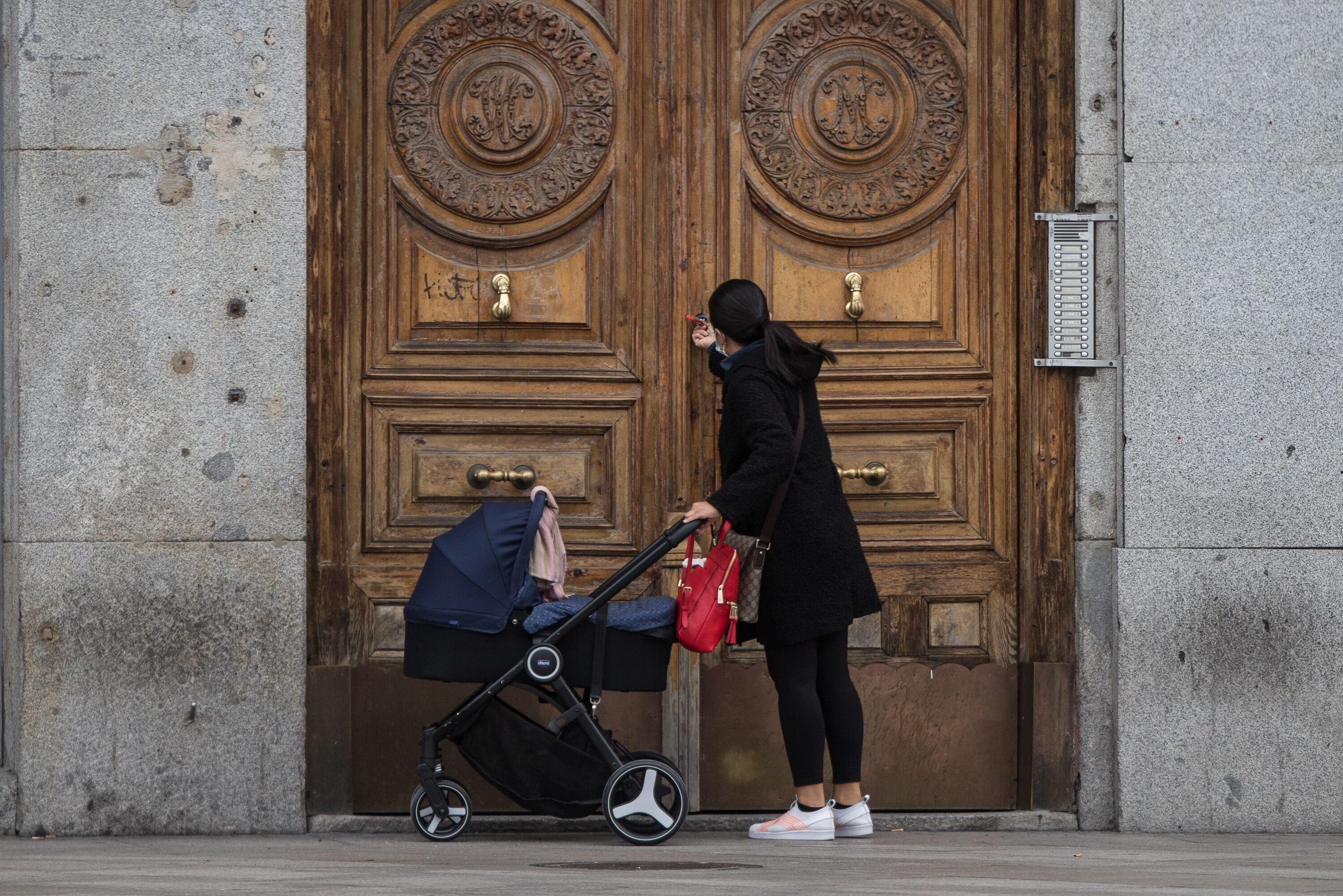 Una mujer frente a un portal de Madrid con un carrito de bebé (Joaquin Corchero/Europa Press)