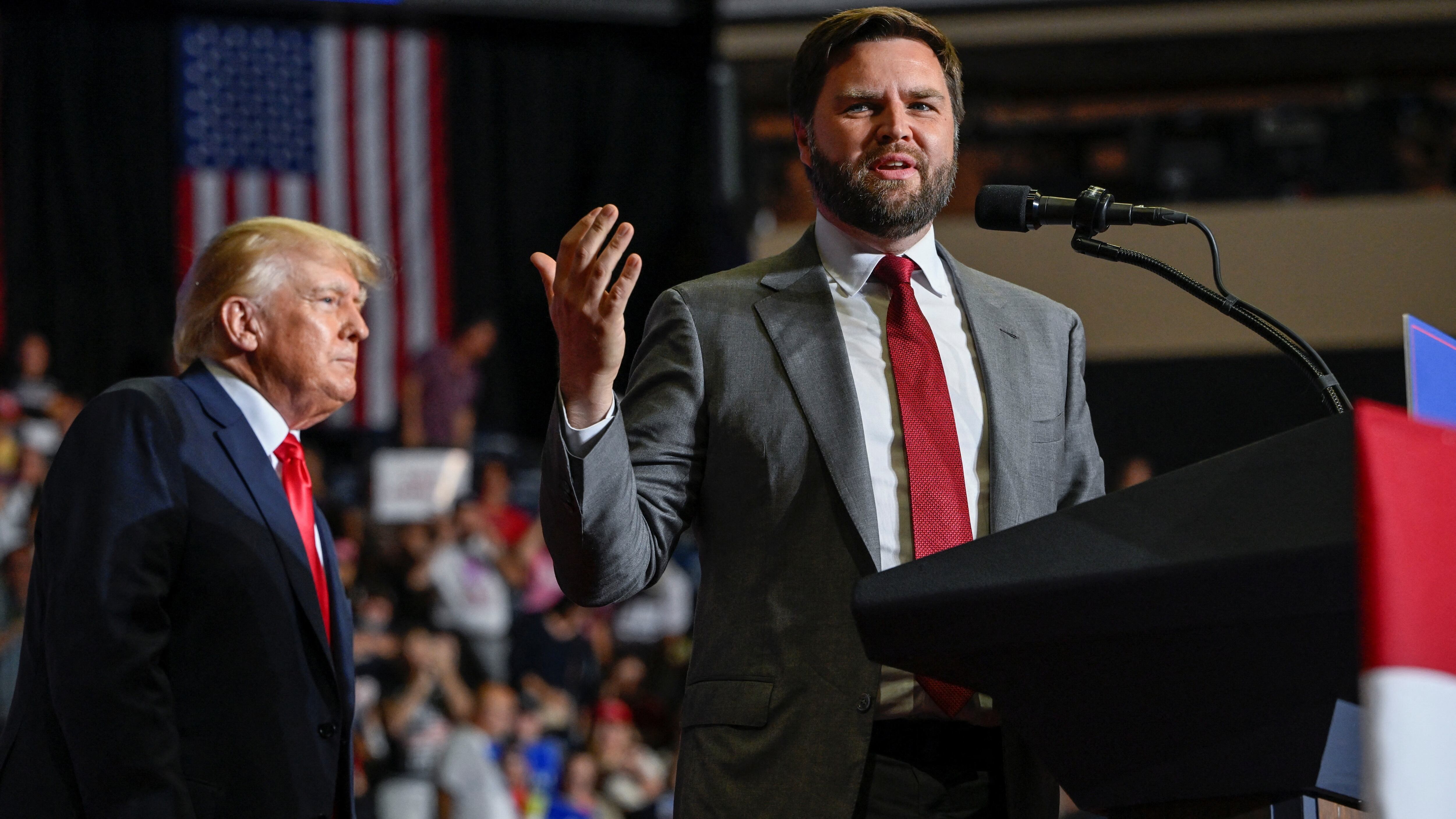 JD Vance habla durante un acto con Donald Trump de fondo (REUTERS/Gaelen Morse)